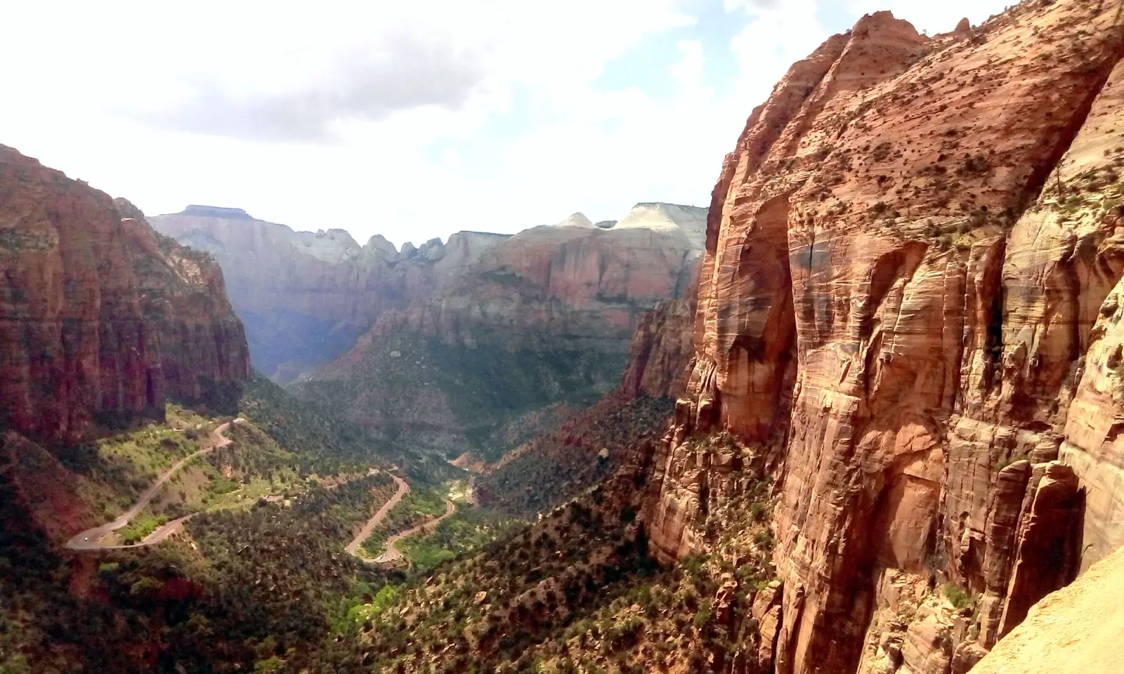 View from Canyon Overlook Point of the Pine Creek switchbacks below with Zion's red sandstone temples in the distance